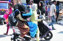 Girls flout traffic rules while riding a two-wheeler in Srinagar. Tribune Photo: anand sharma