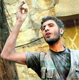 A Syrian rebel gestures after emerging from a building hit by an army tank shell in Aleppo on Monday.