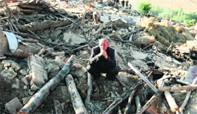 An Iranian resident of Baje-Baj village near Varzaqan town sits on the rubble of his destroyed home.