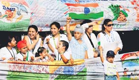 Children and parents display a 50-meter-long graffiti at Sector 17, Chandigarh, on Tuesday