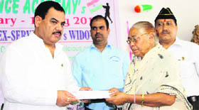 Agriculture and Sainik Welfare Minister Harak Singh Rawat gives a cheque to a widow at a function organised by the Doon Defence Academy in Dehradun on Tuesday.