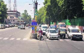 Vehicles wait to cross a junction near traffic lights in Srinagar