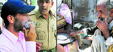 A man smokes a cigarette in front of a policeman; and (right) Despite a ban on smoking at public place, people continue to puff away in the markets of Srinagar