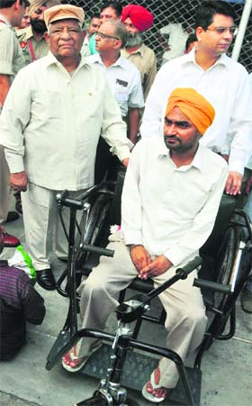 Minister for Local Bodies and Medical Health Chunni Lal presents a tricycle to a physically challenged person in Ludhiana