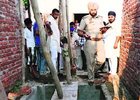 Police officials inspect the septic tank where a three-year-old child died