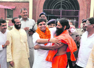 Yoga guru Ramdev receives Balkrishan after his release from Sadhowala jail in Dehradun on Friday. 