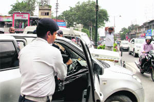 A policeman removes black film from a windowpane of a car during a campaign launched by the traffic police in Dehradun on Friday. 