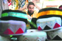 A youth tries a cap ahead of Eid-Ul-Fitr, marking the end of the holy month of Ramadan in Jammu. Tribune photo: Inderjeet Singh