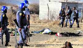 Policemen stand near the bodies of miners killed in police firing near a platinum mine in Marikana.