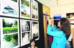A girl clicks a photograph of pictures of eminent photographer Bhumesh Bharati in Dehradun on Saturday.