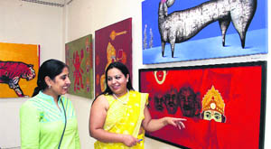 Curator Rosy Varinder Singh shows a painting to a visitor at the exhibition of paintings at the Virsa Vihar in Jalandhar. 