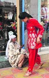An elderly Kashmiri woman begs on the roadside as a girl walks past in Srinagar on the eve of Eid. 