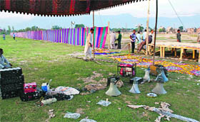 Technicians erect a podium and fix a loud speaker at Eidgah where congregational prayers will be offered on Eid in Srinagar.