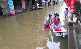 Men use a bathtub to ferry a woman in a flooded street in Hanoi on Saturday