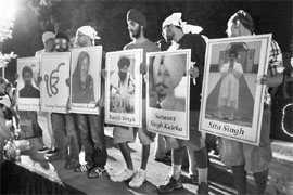 Sikhs hold up placards with photos of six mass shooting victims after a candlelight vigil in Oak Creek, Wisconsin, on August 7, 2012. The killings of six worshippers at a Sikh temple in Wisconsin have thrust attention on white power music, a thrashing, punk-metal genre that sees the white race under siege.