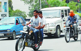 With no policemen on guard, commuters on two-wheelers take a wrong way at the traffic lights and (Right) youths drive motorcycles without helmets. The traffic police says it faces staff shortage.