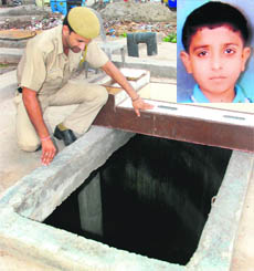 A policeman examines the pit in which Sumit (inset) fell at Shanti Nagar in Mani Majra on Monday. 