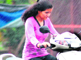 A girl faces a tough time riding a scooter as rain lashed Haridwar on Monday.