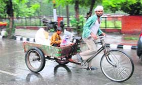 A rickshaw-puller takes his children home during rains in Karnal
