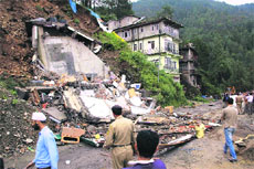Onlookers gather near the debris after a house collapse due to heavy rain in Shimla on Monday.