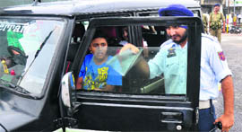 A traffic policeman removes a black film from a vehicle in Jammu on Monday. The police will start impounding vehicles violating the Supreme Court directive from Tuesday.