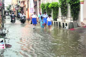 Students wade through a waterlogged street in Rohtak on Tuesday