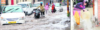 People wade through a waterlogged road and (right) a woman throws rainwater out of her house in Amritsar on Wednesday. 