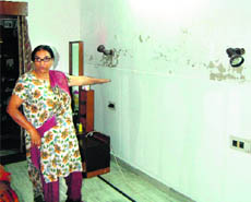 Sawinder Gill points to a wall hit by water leakage at her house in Amritsar on Wednesday. 
