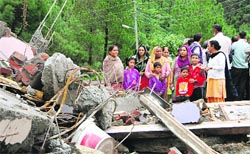 A family stands near the debris of a collapsed building at Totu in Shimla on Wednesday. Photo: Amit Kanwar