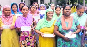 Beneficiaries of the Slum Development Housing Scheme show the cheques issued to them at the MC office in Jalandhar on Wednesday