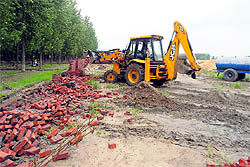 A boundary wall of an illegal colony being demolished in Ludhiana on Wednesday