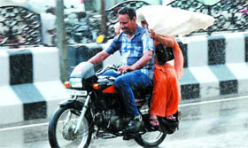 A woman tries to shield herself from the rain even as her co-passenger gets wet in the shower.