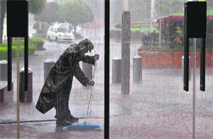 An employee of a hotel sweeps water to prevent it from entering the hotel lobby during heavy rainfall in Hyderabad on Friday.