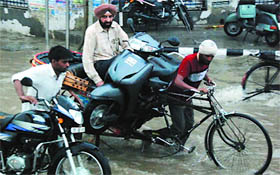 A man carries his scooter on a rickshaw after it broke down near Fauji Chowk.