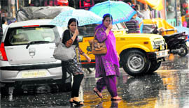 Afternoon showers brought much-needed respite to the people of Srinagar on Saturday. Two women cover their head with umbrellas in a market.