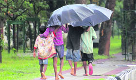 Children cover themselves under umbrellas while it drizzled in Karnal.