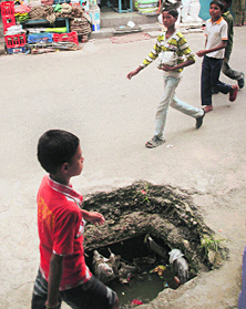 A boy walks past an open manhole at a market in Shakti Nagar, Jammu.