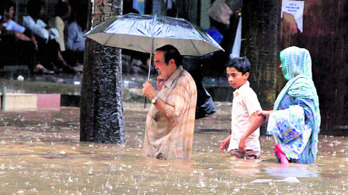 People wade through a waterlogged street during Mondays heavy downpour in Mumbai.