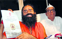 Yoga guru Ramdev shows a copy of the CAG report on the coal scam in Haridwar on Tuesday