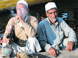 A boatman smokes a hookah in his shikara at Dal Lake in Srinagar