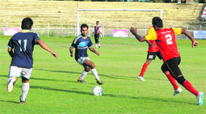Members of Karnataka (red) and Uttar Pradesh (blue) teams clash in the semifinal of All-India Postal Football Tournament at Bakshi Stadium in Srinagar on Tuesday. Karnataka won the match two goals to none.