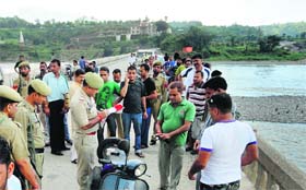 Police officers examine the spot on the Baradhari bridge in Reasi from where a young couple jumped into the Chenab river on Wednesday
