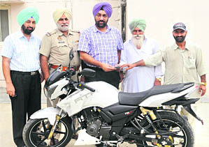 Farmers hand over keys of a bike to DSP Shahkot on Wednesday.