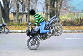 A youngster performs a stunt on a bike on the Boulevard Road in Srinagar