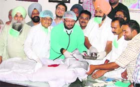 Congress leader KK Bawa (in green coat) performs a “brain surgery” on an effigy of the Punjab Chief Minister and the Dy CM in protest against the hike in taxes in Ludhiana