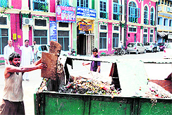 A Municipal Corporation employee lifts garbage from outside Arya Samaj Senior Secondary School