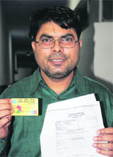 The victim, Vijender Singh, shows his ATM card and a copy of the complaint.