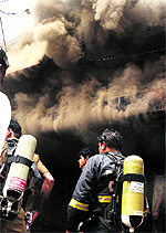 Firemen enter a godown at Burail village where a fire broke out on Friday