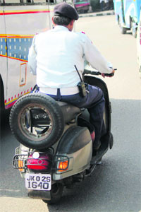 A traffic policeman drives a scooter without wearing a helmet in Jammu on Friday.
