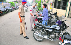 Policemen challan a motorcyclist outside GGN Khalsa College in Ludhiana.